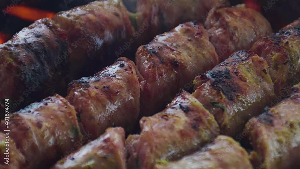 Unos deliciosos chorizos de chancho y pollo cubiertos de salsas y aceite vegetal  asándose en una parrilla cacera y grande en una casa de verano. Deliciosa comida. 