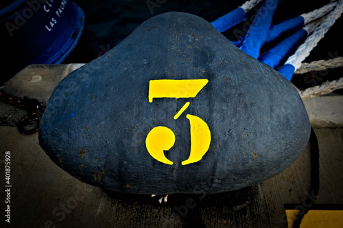 Number 3, three, a large yellow digit on a black harbor bollard. photo