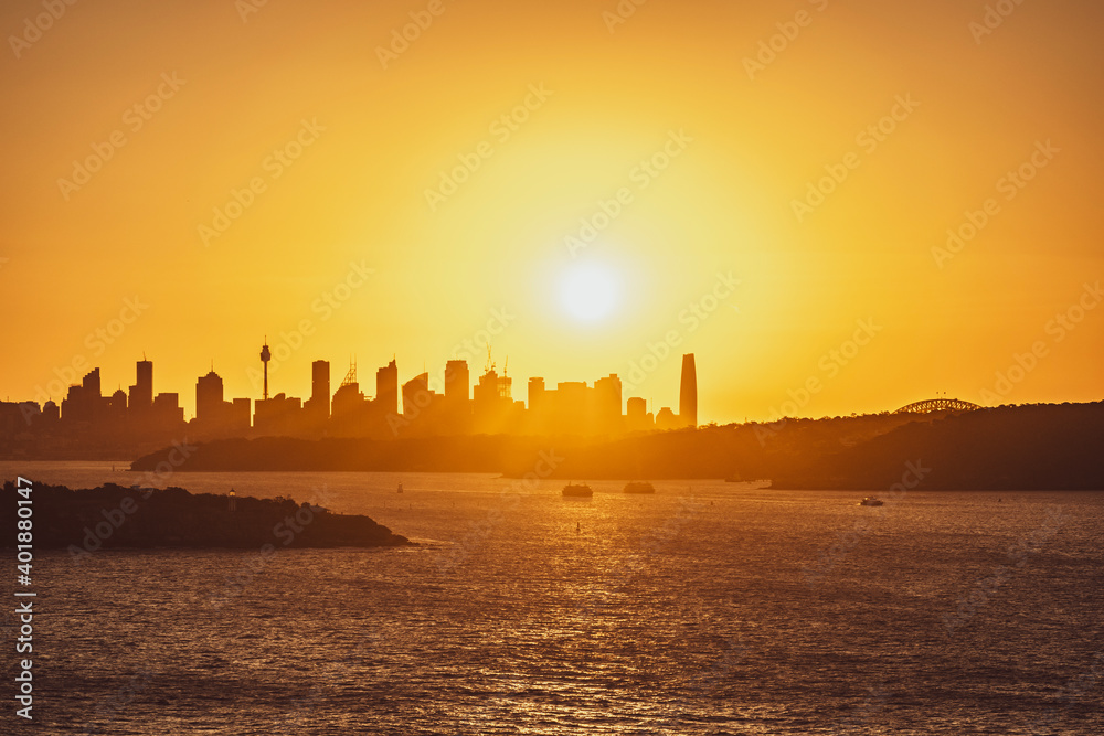 Beautiful evening sunset shot of the Sydney Harbour with the Sydney skyline in the background, seen from Fairfax Lookout at North Head Sanctuary. Shot in December 2020. Boats cruising in harbour.