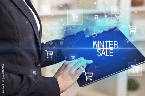 Young person makes a purchase through online shopping application with WINTER SALE inscription