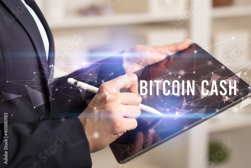 Close up hands using tablet with BITCOIN CASH inscription, modern business technology concept