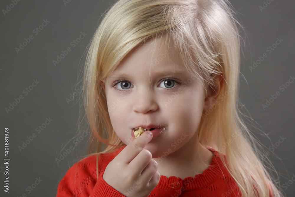 Head shot of cute little girl eating cookie
