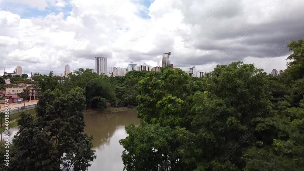 Drone voando para cima revelando a cidade atrás da floresta