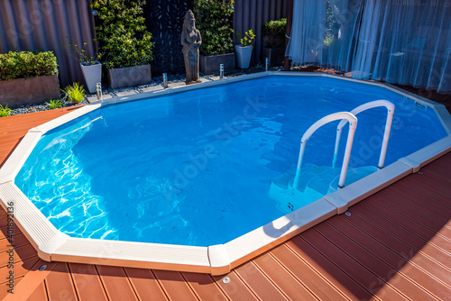 Above ground pool sunken below ground and surrounded by decking.