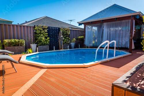 Above ground pool sunken below ground and surrounded by decking.