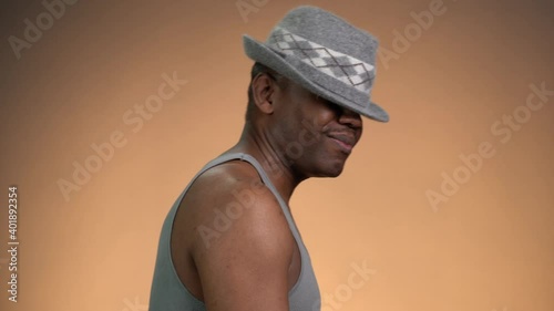 African American man dancing wearing hat on snapping his fingers in tang top profile view