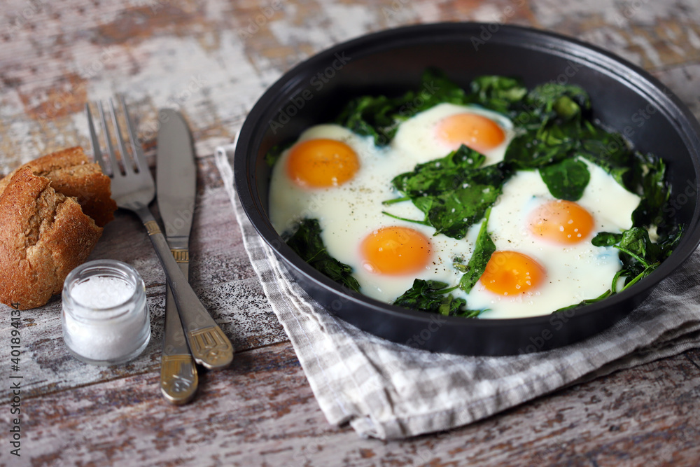 Eggs with spinach in a frying pan. Healthy breakfast. The keto diet. Eggs with spinach in a frying pan. Healthy breakfast. The keto diet.