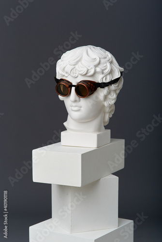 Plaster head of Antinous with round glasses. The concept of the absurd and the combination of the incongruous
