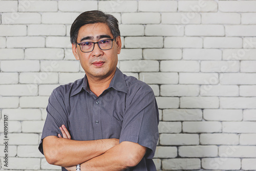 Foto Portrait of Asian handsome senior elderly man wear eyeglasses on white brick wall background