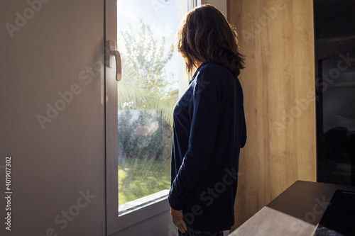 An attractive female standing in a room by a window