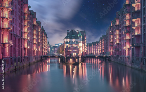 A wonderful shot of  Fleetschloesschen, Speicherstadt,  Hamburg, Germany during the nighttime with the reflection in the water and with starry sky photo