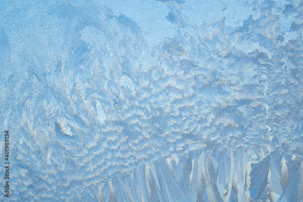 Winter frosty patterns on the window. Frozen glass texture. Abstract blue background.