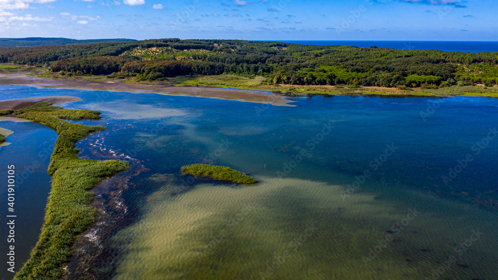 A panoramic shot from Durugol Turkey. There is a lake near a path filled with forest and green grass under the blue sky.