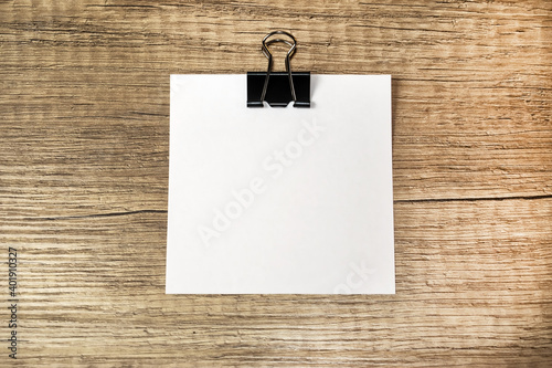 Blank white sheet with stationery clip on wooden surface. Template for corporate identity. Concept photo