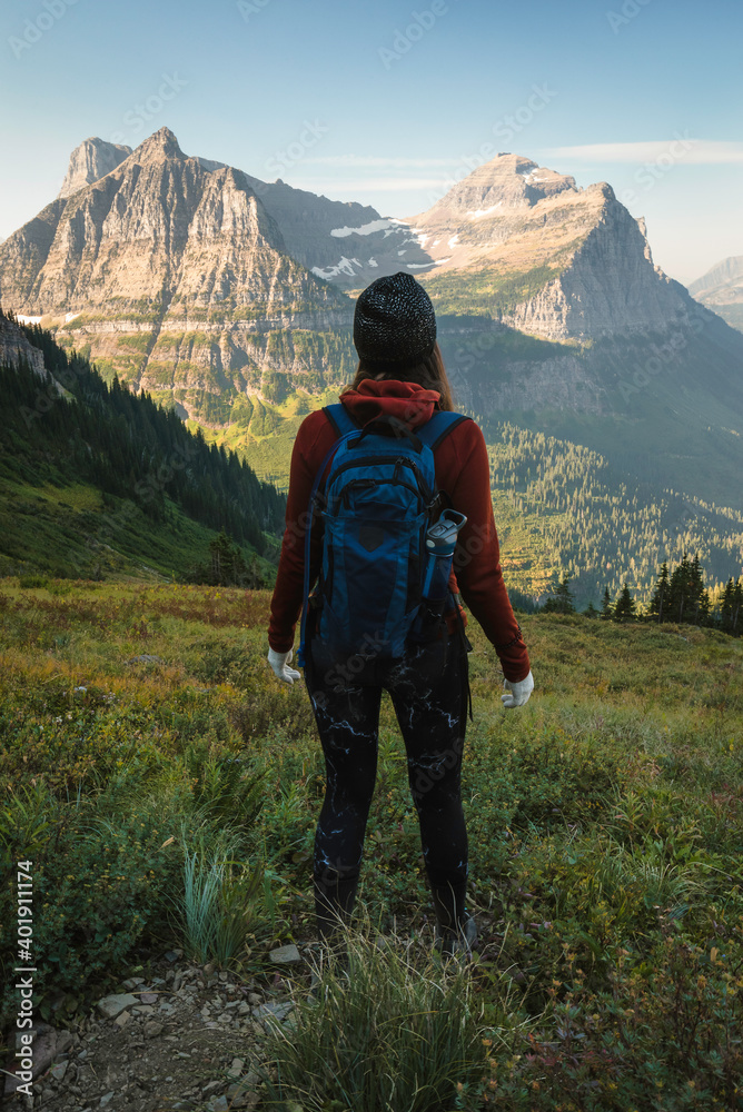 A young woman hikes through the mountains in Glacier National Park on a beautiful summer day