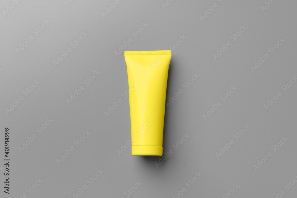 Yellow cosmetic container on gray background top view Yellow cosmetic container on gray background top view