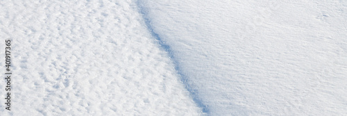 Beautiful winter background with snowy ground. Natural snow texture. Wind sculpted patterns on snow surface. Wide panoramic texture for background and design. Closeup top view with copy space. © Andrei Stepanov
