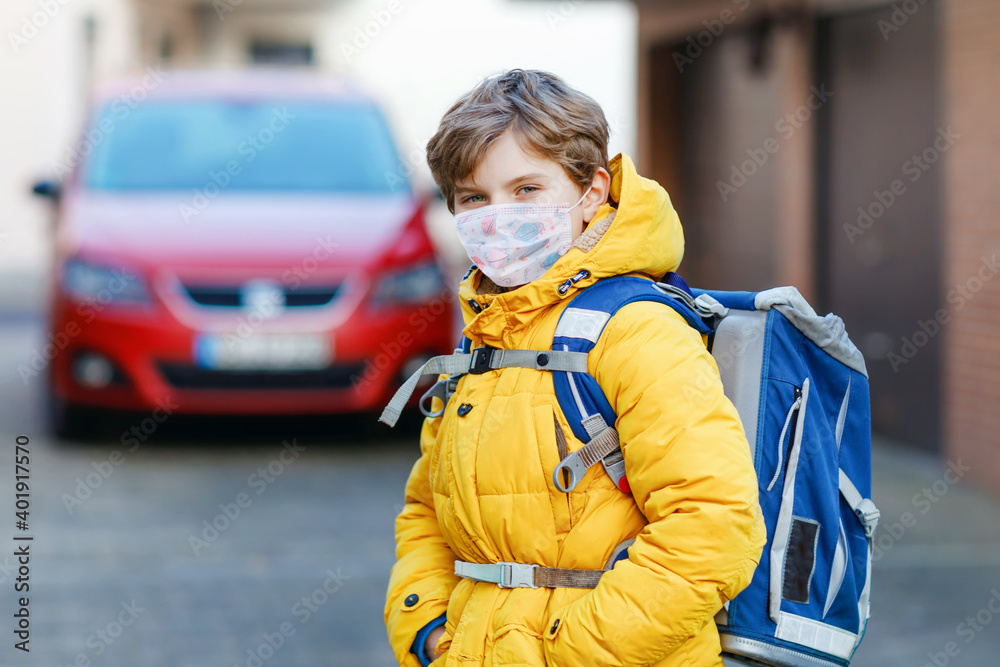 Little kid boy wearing medical mask on the way to school. Child backpack satchel. Schoolkid on cold autumn or winter day with warm clothes. Lockdown and quarantine time during corona pandemic disease Little kid boy wearing medical mask on the way to school. Child backpack satchel. Schoolkid on cold autumn or winter day with warm clothes. Lockdown and quarantine time during corona pandemic disease