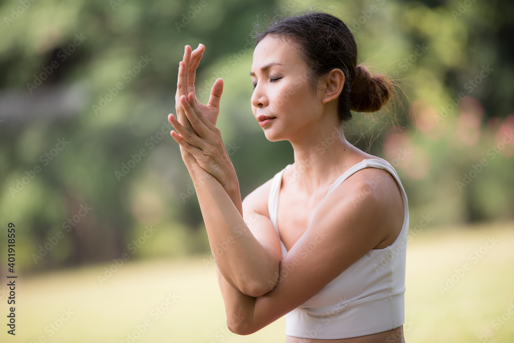 Asian model poses yoga in a park on a natural green background, health care concept, beautiful body structure, fit body