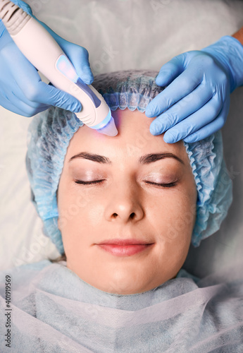 Photography Close up of beautician hands in sterile gloves using aqua peel water galvanic device while cleaning and exfoliating woman face