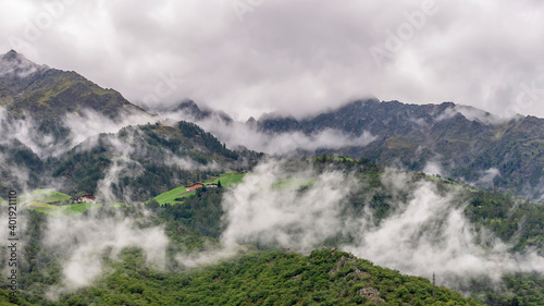 The Alps above Naturno, South Tyrol, Italy, partially covered by layers of low white clouds