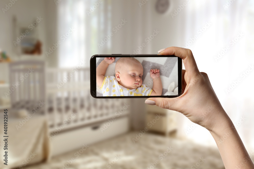 Mother using modern mobile phone as baby monitor at home
