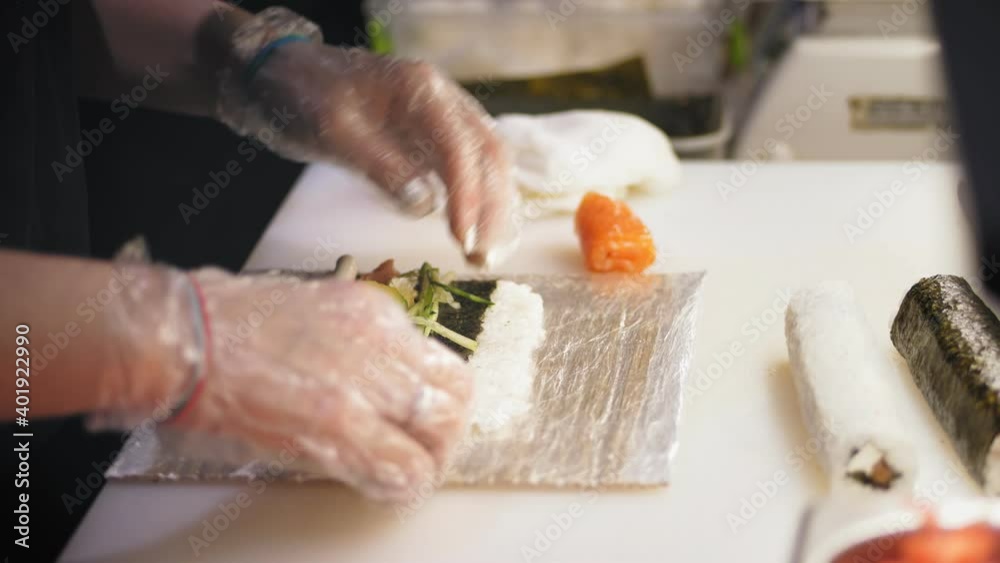 Traditional Japanese food. close-up. Making Sushi Rolls at professional kitchen of sushi bar or restaurant. Sushi Chefs hands are wrapping the nori sheet with ingredients. Traditional Japanese food. close-up. Making Sushi Rolls at professional kitchen of sushi bar or restaurant. Sushi Chefs hands are wrapping the nori sheet with ingredients.