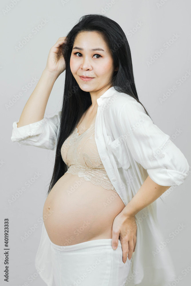 Portrait of young happy smiling pregnant asian woman,Pregnancy health care preparing for baby concept isolated on gray background Portrait of young happy smiling pregnant asian woman,Pregnancy health care preparing for baby concept isolated on gray background