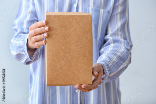 Woman with cardboard box on light background