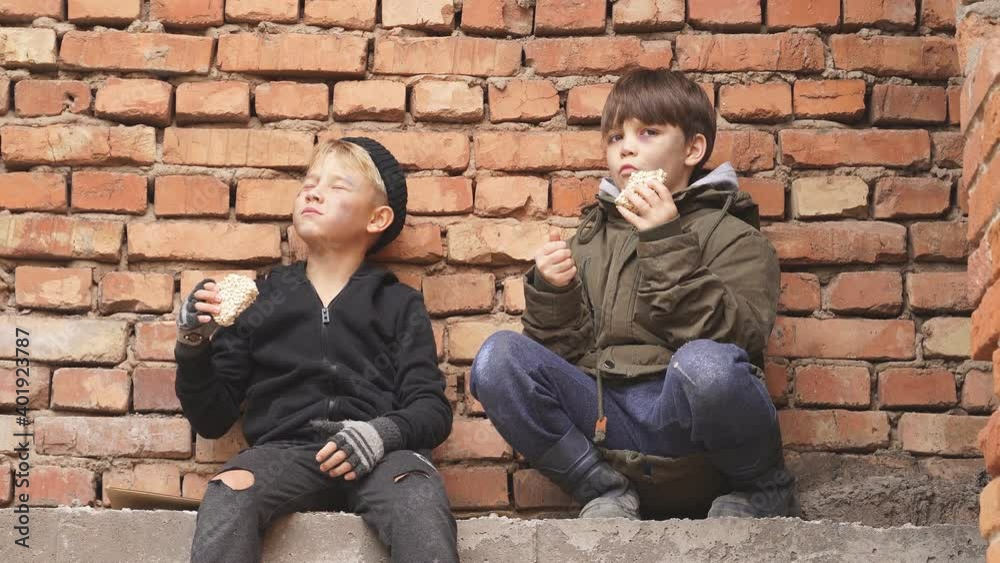 Hungry street boys looking for food outdoors, wearing dirty clothes. Homeless people concept Hungry street boys looking for food outdoors, wearing dirty clothes. Homeless people concept