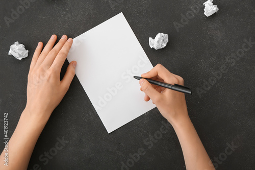 Woman with blank paper on dark background