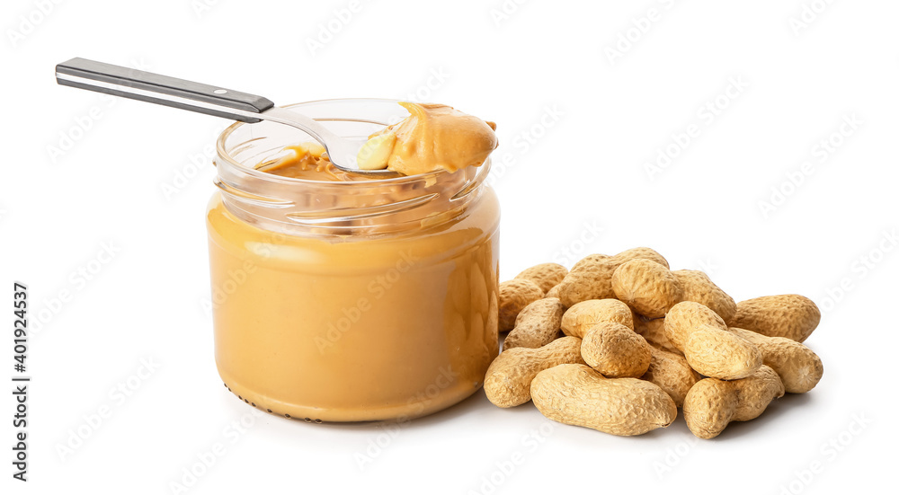 Jar and spoon with tasty peanut butter on white background Jar and spoon with tasty peanut butter on white background