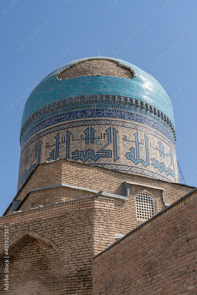 The ancient Kok Gumbaz or blue dome, the madrasa of Abdullatif Sultan in Istaravshan, Sughd province, Tajikistan seen from a backstreet with kufic script