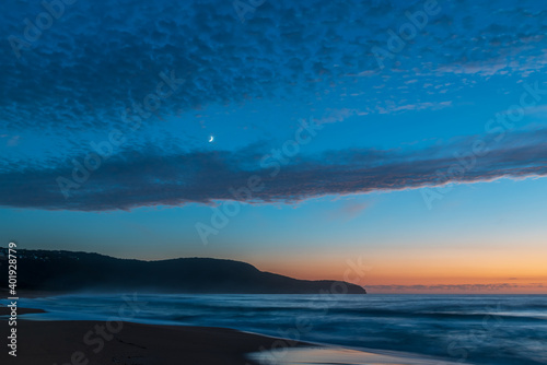 High cloud, partial moon and a pretty blue dawn at the beach © Merrillie