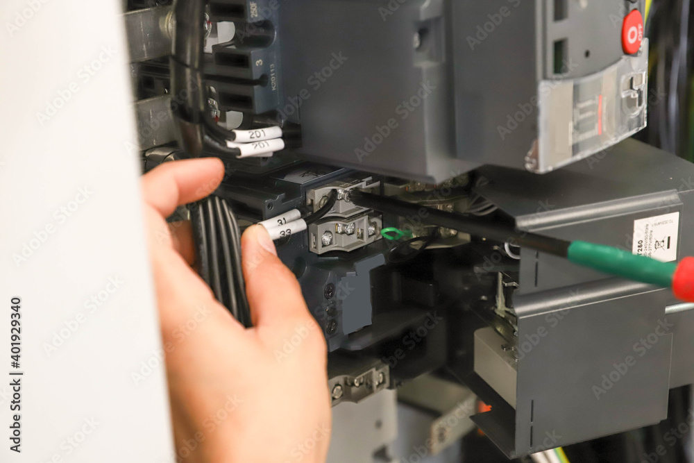 The technician is using a screwdriver Screw the nut to secure the device to the electric wire. The technician is using a screwdriver Screw the nut to secure the device to the electric wire.