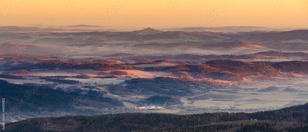 Fototapeta premium Panorama of a mountain valley shrouded in morning mists seen from the top of the Karkonosze mountain range in Poland
