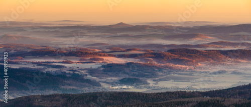 Panorama of a mountain valley shrouded in morning mists seen from the top of the Karkonosze mountain range in Poland