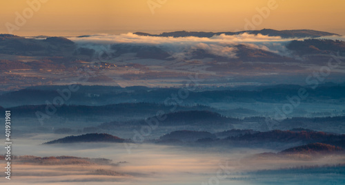 Panorama of a mountain valley shrouded in morning mists seen from the top of the Karkonosze mountain range in Poland