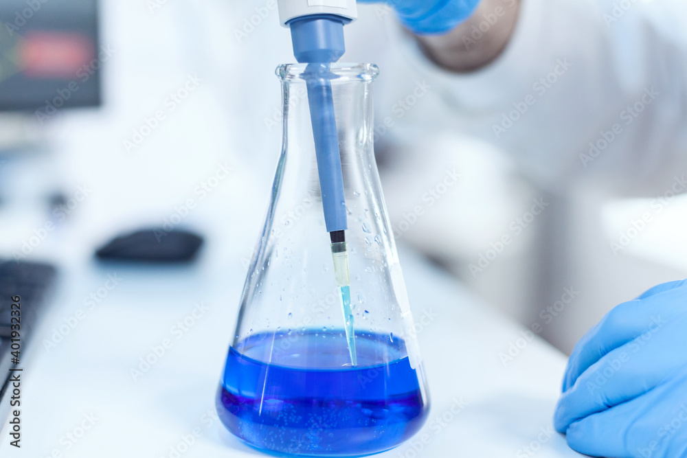 Scientist mesuaring genetic material with micro pipette in laboratory. Senior professional chemist using pippete with blue solution for microbiology tests. Scientist mesuaring genetic material with micro pipette in laboratory. Senior professional chemist using pippete with blue solution for microbiology tests.