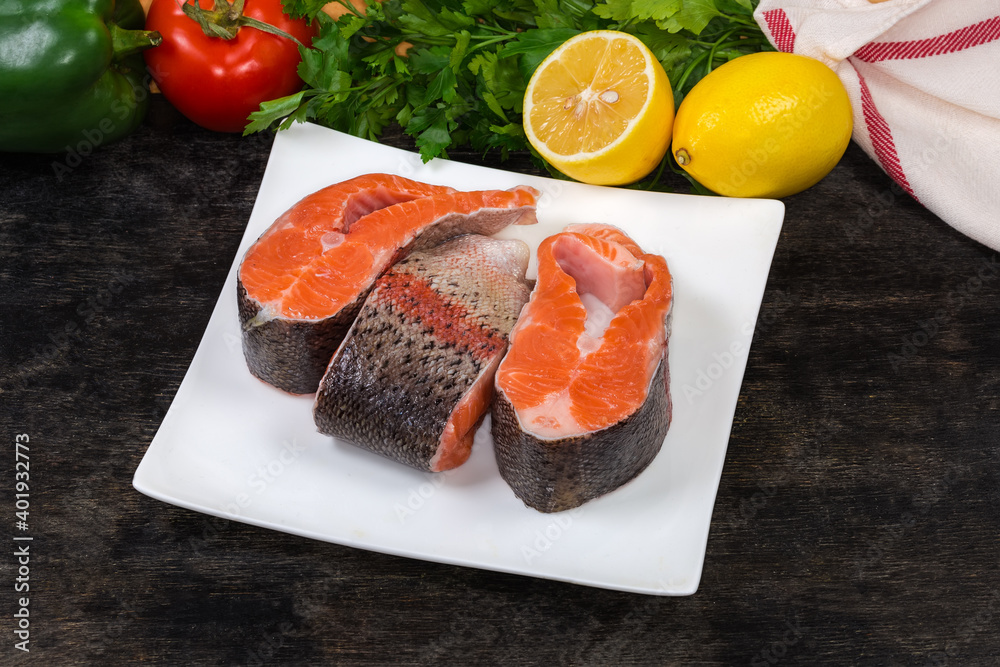 Uncooked trout pieces on square dish on a black surface Uncooked trout pieces on square dish on a black surface