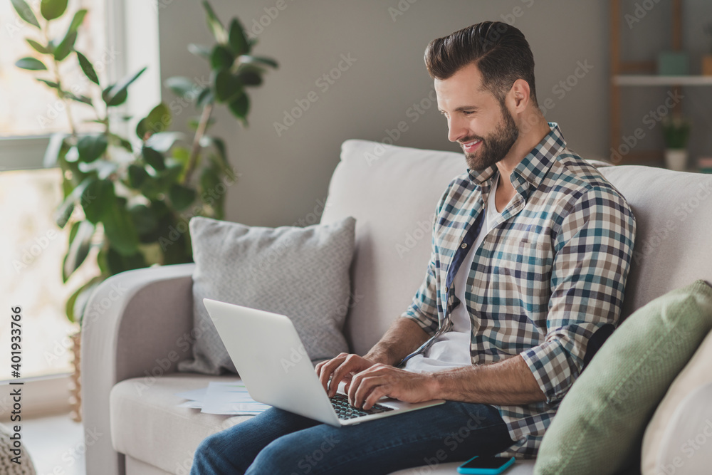 Profile side photo of young handsome man happy positive smile read browse internet laptop distance work sit couch house