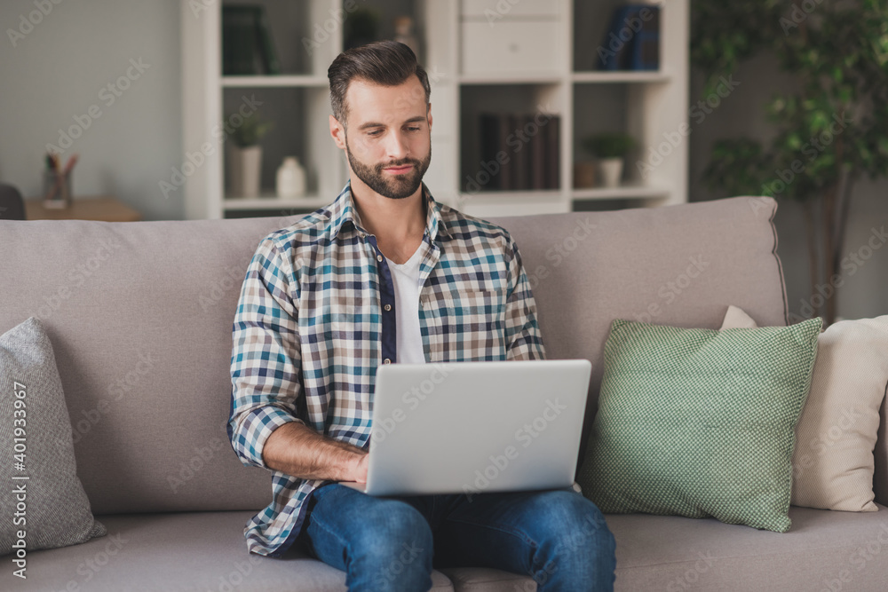 Photo of young handsome brown hair business man sit couch home work laptop type report wear casual outfit Photo of young handsome brown hair business man sit couch home work laptop type report wear casual outfit