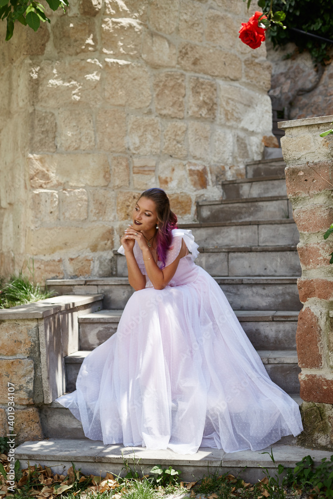 Woman bride is sitting on the stairs and waiting for her groom. Woman with purple hair in a beautiful wedding dress Woman bride is sitting on the stairs and waiting for her groom. Woman with purple hair in a beautiful wedding dress