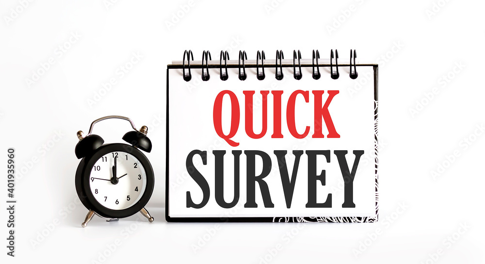 Quick Survey. notepad writing on the white background with alarm clock Quick Survey. notepad writing on the white background with alarm clock