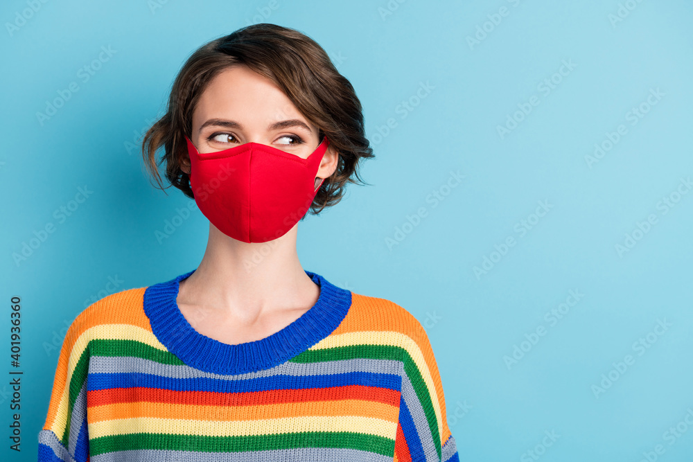 Close-up portrait of nice curious minded girl wearing red reusable textile mask looking aside copy space isolated over bright blue color background Close-up portrait of nice curious minded girl wearing red reusable textile mask looking aside copy space isolated over bright blue color background