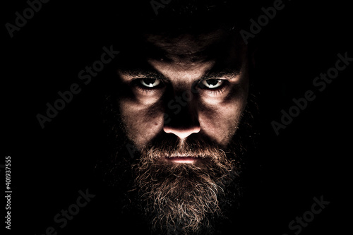 Stern, bearded man looking out of the darkness