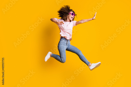 Photo portrait full body view of woman kicking jumping up isolated on vivid yellow colored background