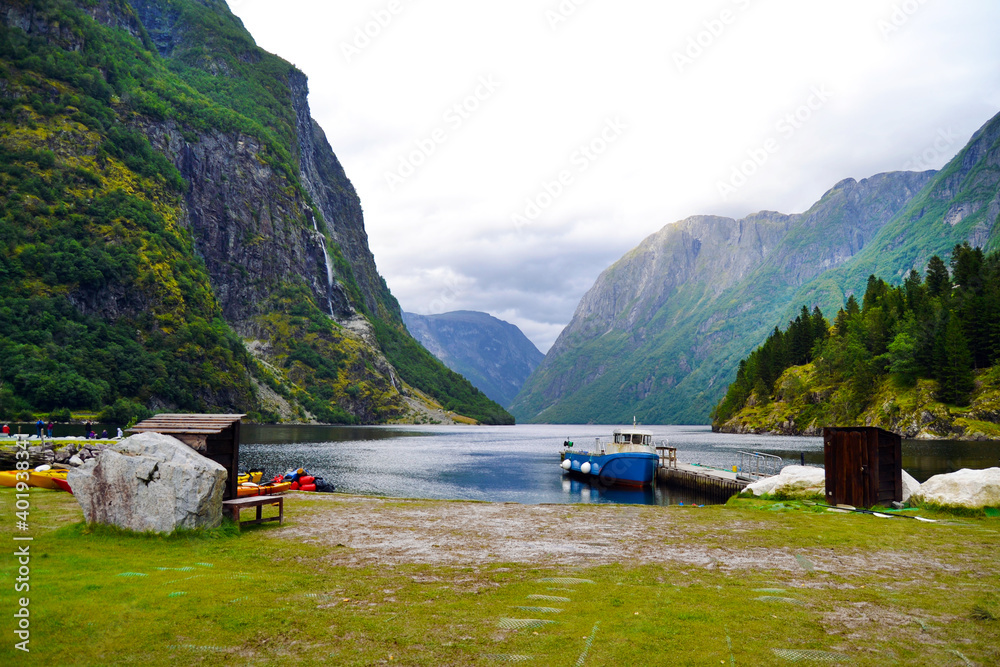 Beautiful idyllic mountain landscape. Gudvangen, the popular tourist village located at the end of the Naeroyfjord. The boat on the foreground.