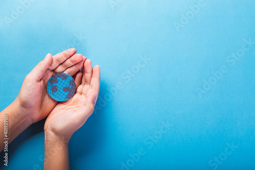 Hands holding the planet Earth on a blue background - Save the world, creative concept, environmental pollution or World Earth Day.
