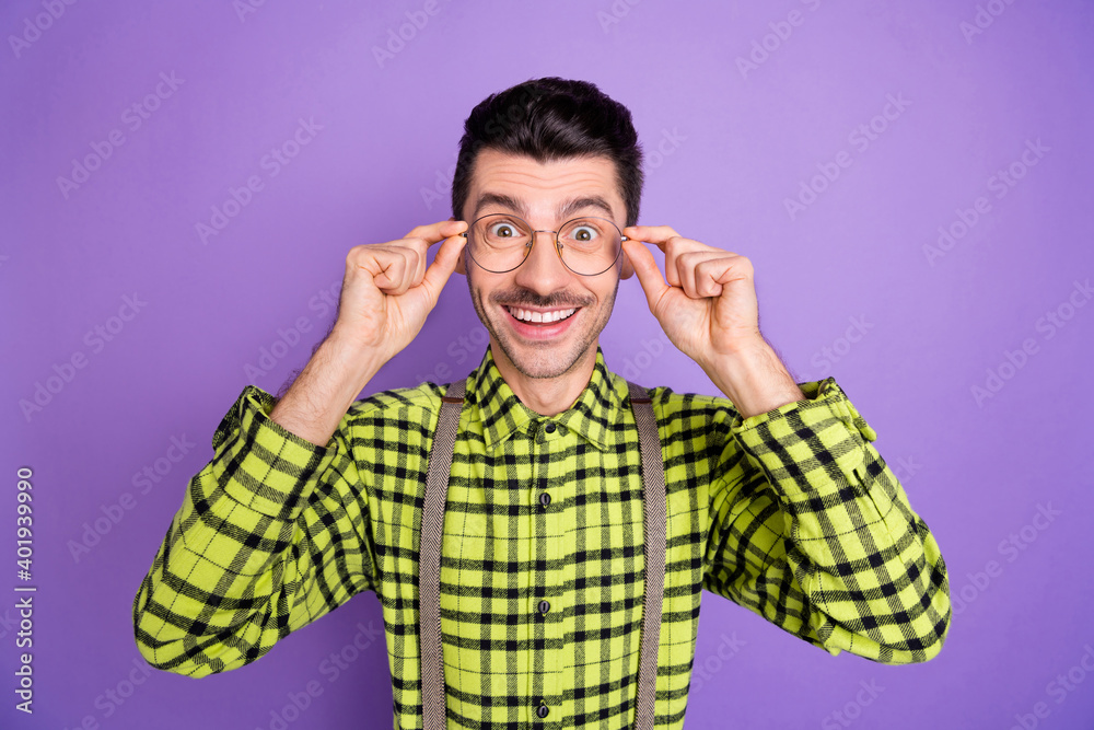 Photo portrait of smiling excited guy touching glasses with two hands isolated on vivid violet colored background Photo portrait of smiling excited guy touching glasses with two hands isolated on vivid violet colored background
